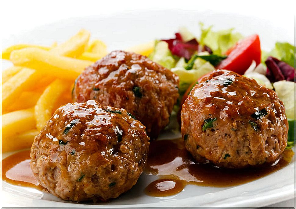 Plate with meatballs in sauce, potatoes and salad.