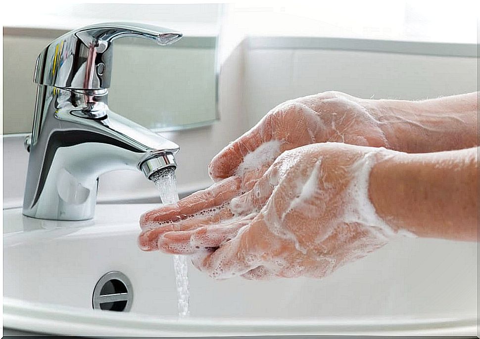 Soapy hands under running water from a tap.